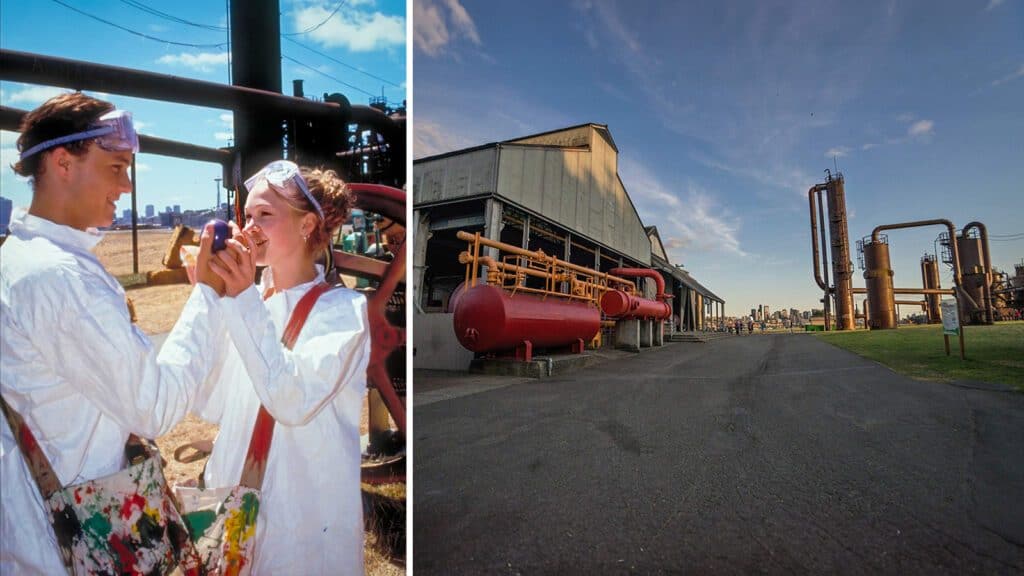 Left: two smiling young adults wearing paint-splattered overalls photograph each other with a smartphone. Right: industrial landscape with pipes and steel structures under a blue sky during the "10 Things I Hate