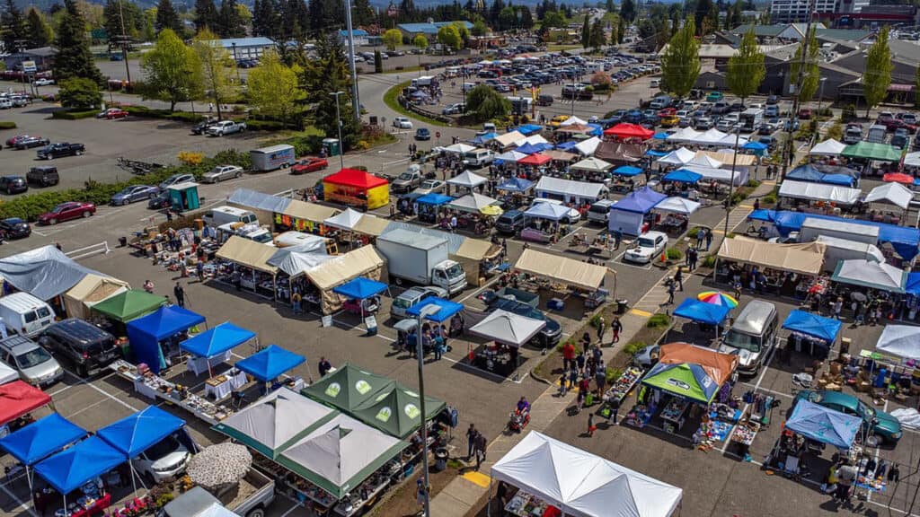 Aerial view of a bustling flea market with colorful stalls and hidden gems, attracting numerous shoppers.