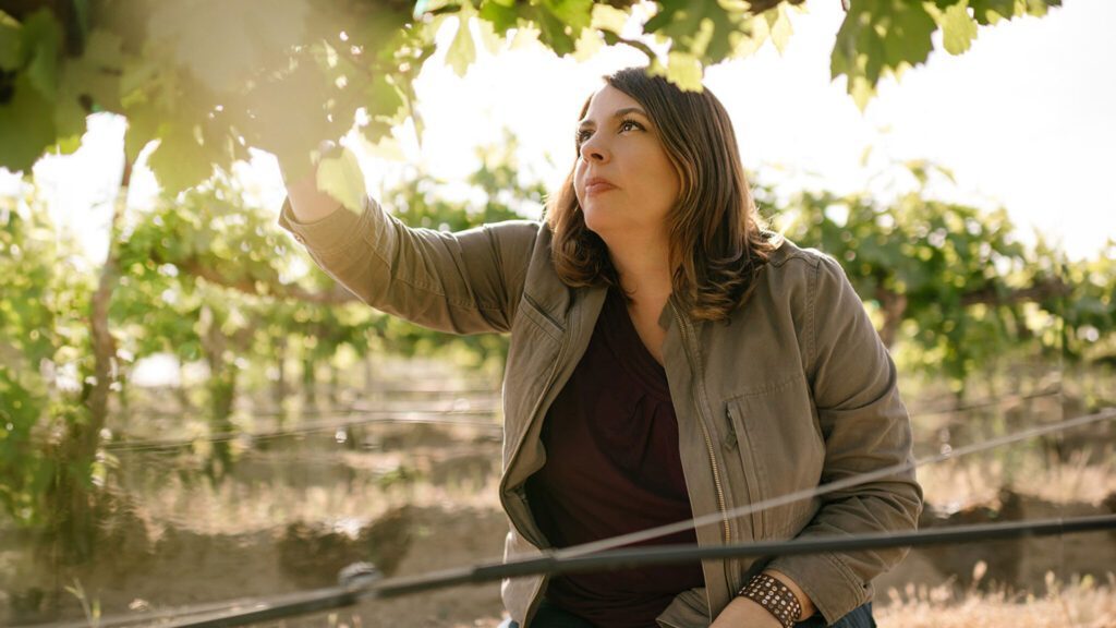 Woman inspecting grape leaves in a vineyard during a wine country weekend getaway.