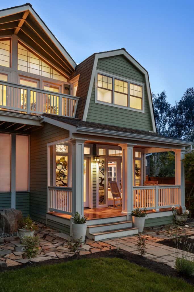 Full image of the front of the house, featuring a warm color palette that includes a warm pistachio green for the siding. The shot was taken in the evening and the interior and exterior lighting gives the house a soft and inviting look.