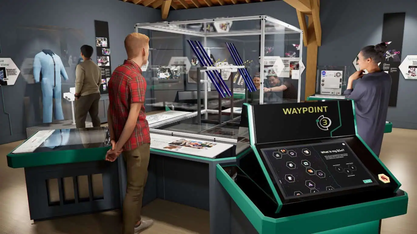 People are observing various displays and exhibits in a modern technology museum, including a central glass case with a model and an interactive touchscreen labeled "WAYPOINT," reminiscent of those found at the renowned Museum of Flight, that explores life in orbit.