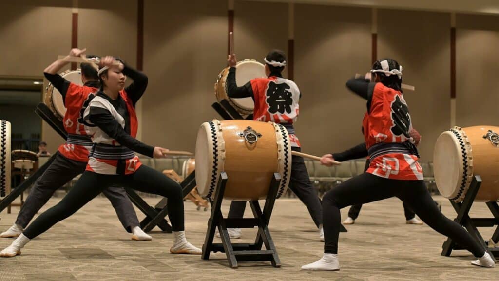 A group of performers in traditional attire playing taiko drums.