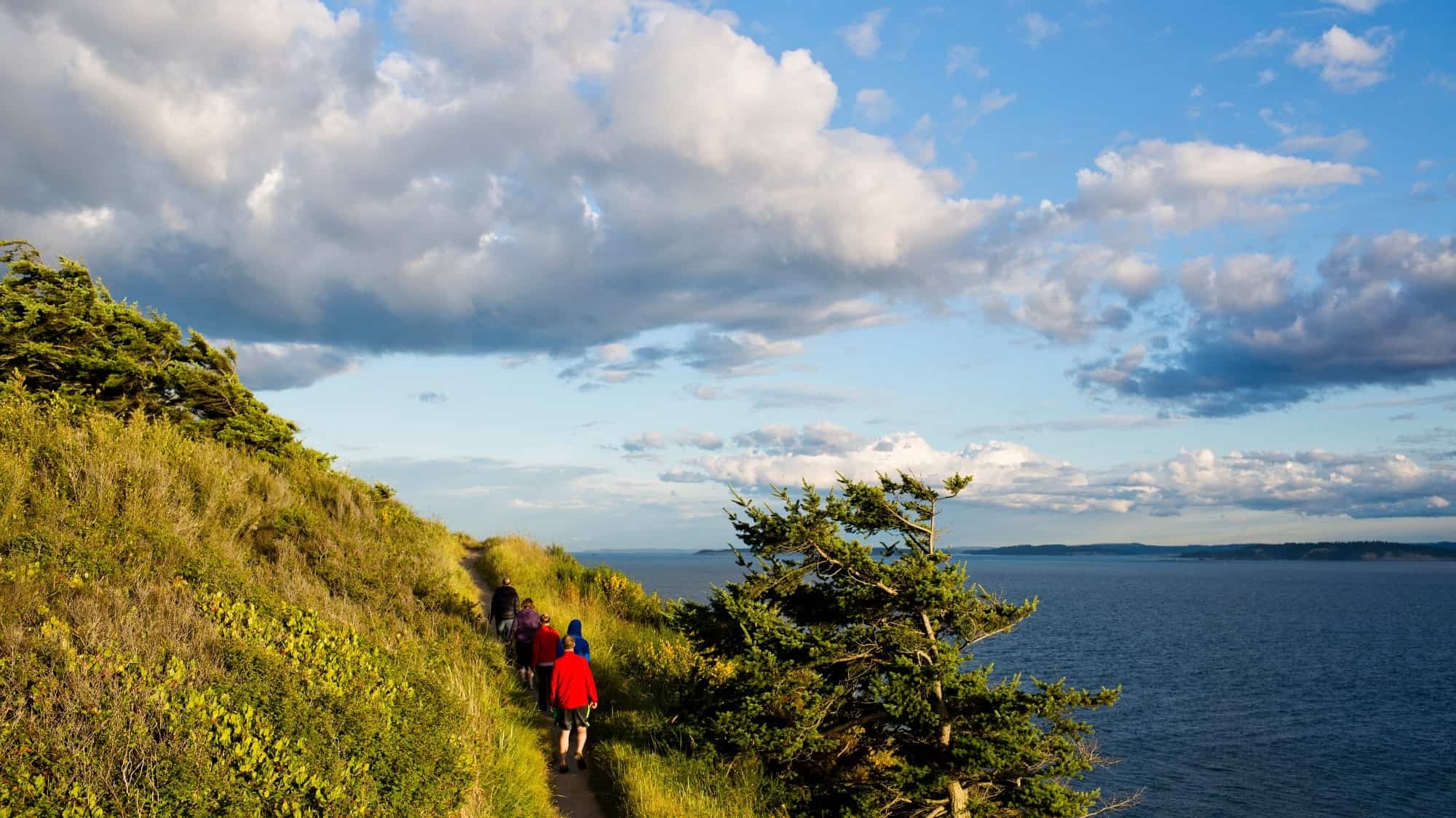 Hikers on a coastal trail with views of the sea and sky at dusk during an island hopping tour.